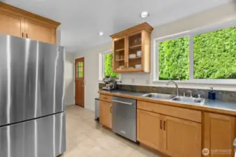 Lovely shaker-style cabinetry with glass doors and crowm molding contribute to the overall quality feel of this home.  Note the convenient outside access door here; facing it is the glorious walk-in-pantry, and the staircase to the basement!