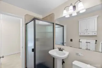Hall bath for guests/family continues the fresh feel with tiled shower, large mirror, and pedestal sink; built-in linen cabinet just outside the doorway in the hall; privacy window allows for more natural light.