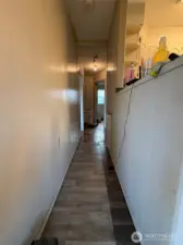 To the right is the kitchen and on the other side of the wall is the living room.  As noted, if the wall was removed, the kitchen and living room would be updated to be an open space including dining.  Down the hall are two bedrooms and the main full bathroom