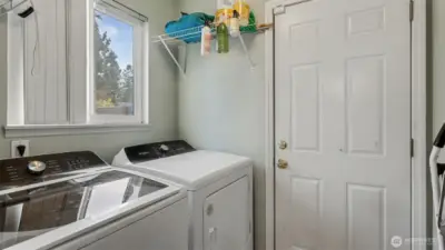 Bright laundry area with window and shelving for storage