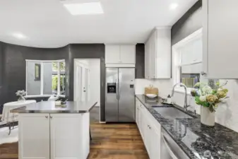 The kitchen with a view of the breakfast nook and the hallway leading to the primary suite.