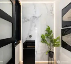 The powder room features a backlit marble slab that beautifully showcases the Italian glass pedestal sink—so chic!