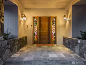 Large entry with stone planters and custom stained glass sidelights.