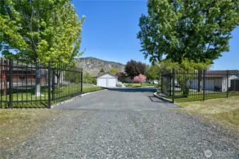 A long, gated drive stretches ahead, offering a sense of privacy, security, and a grand welcome to the serene property beyond.