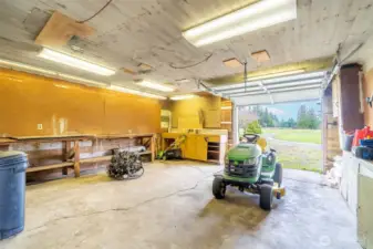 One end of the shop includes a roll-up garage door and concrete flooring for yard equipment.