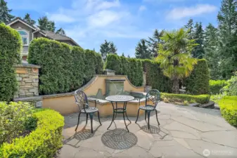 Charming fountain inspired sitting area at the front of the home offers a serene spot to relax and enjoy the beautifully landscaped surroundings.