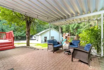 Cozy covered paver patio, outdoor lighting, with room for patio furniture, & fire pit. Spacious backyard, play structure. Perfect for outdoor living!