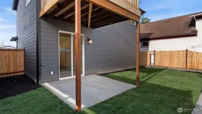 Fully fenced and landscaped backyard has covered patio.