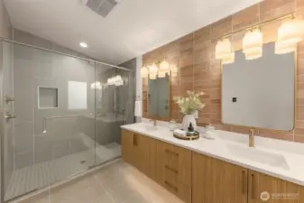 Spa caliber primary bath with a frameless glass shower, double vanity, and statement wall tile. Warm wood tones balance the modern palette.