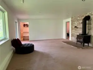 Rec room with wood stove, showing the entry to the spacious full bath in the left corner and door to the bonus room in the right corner.