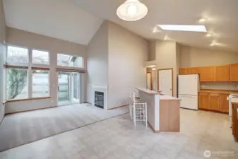 Looking from the large kitchen dining area towards the bright family room with gas fireplace and slider to the fenced backyard and patio.
