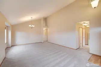 Living room looking towards the hallway on the right leads to the 2 front closets on the right and the main bath on the left of the hall. Bedrooms 2 and 3 are just down the hall. The hallway at the back of the room leads straight through to the kitchen with dining space and family room. Primary suite and laundry room are down the shrt hal to the right.