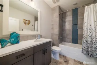 Main bathroom downstairs with a tub shower combination. Large tub, ceiling high tiles and vinyl tile floors make this bathroom more durable for your rough and tumble house guests! Lots of storage here, too!