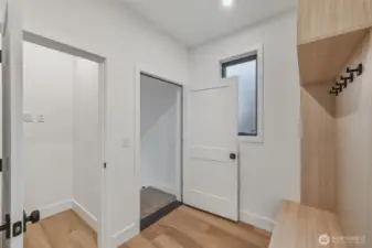 A view of the mud room area with built in shelving and under stair storage closet, just off the garage entrance.