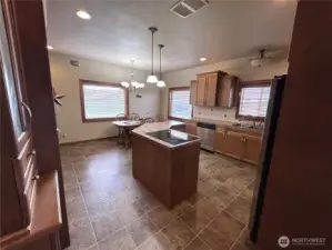 View of kitchen from family room. Island with stove.Easy cleaning laminate flooring and counters