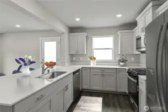 Photo is for Light-filled kitchen featuring quartz countertops, stainless steel appliances, and a spacious center island