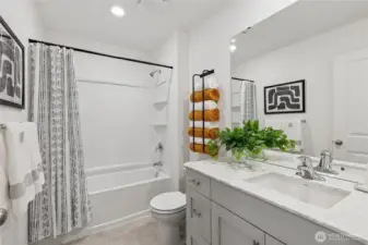 Full bath with tub and quartz countertops.