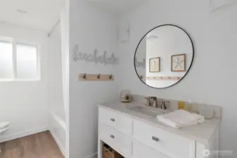 The guest bath has been fully remodeled and offers a fresh, modern feel with a beautiful vanity, updated flooring, stylish lighting, and a sleek tub/shower combination—designed for both comfort and elegance.