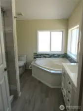 JETTED TUB IN CORNED, GLASS TILE ACCENT WALL TRIM.