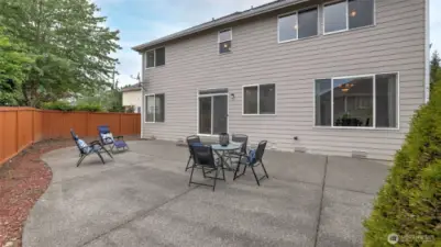 The backyard is perfect for BBQs and outdoor activities, featuring a large concrete patio with plenty of space for hosting gatherings and events