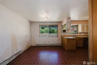 Dining area has window looking out to large grassy area. The walls had wallpaper that is peeling off. The baseboard is a radiant heating system that currently doesn't function and can be removed and replaced with a minisplit heating airconditioning system for example.