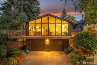 Chalet-inspired façade framed by heritage trees on a tranquil bend of 12th Avenue West, with soaring windows above a coveted 2-car garage and three additional off-street spaces.