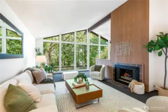 A dramatic entrance opens to soaring ceilings and a double-sided fireplace, with a wall of glass framing woodland privacy and seasonal light.”