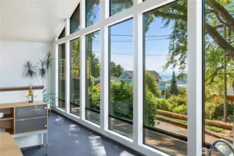 A wall of windows frames heritage trees and glimpses of Puget Sound, merging calm greenery with horizon views that stir a sense of wonder.