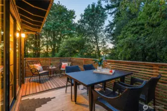 Lanai dining deck, approx. 12 by 7 feet, extends seamlessly from the dining room, offering a woodland-wrapped space for meals and gatherings.