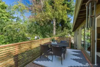 Lanai with distinct dining and lounge zones, opening to a lower stone patio with fountain—an inviting garden connection and natural transition to the flexible lower level with ADU potential.