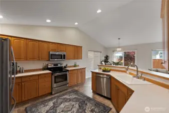 Open and airy kitchen with vaulted ceilings, stainless steel appliances, and a wide breakfast bar overlooking the dining and living areas—perfect for entertaining or family gatherings.