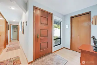 The welcoming entry, with the front door in the center, a coat/storage/hot water tank closet is on the right, and the hallway on the left leads to two guest bedrooms, a full bath, and the laundry closet with washer & dryer.