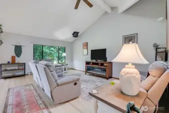 The main living area has vaulted ceilings with a skylight, wood beams, newer Rustic Legacy Laminate Wood Floor. In the background is a vented pipe for a fireplace or stove.