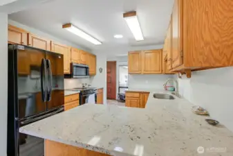 The spacious kitchen has electric appliances, a newer granite counter top and kitchen sink and plentiful cabinet space.