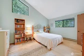 The lovely primary bedroom is spacious, light and bright with vaulted ceilings, and newer light oak laminate hardwood floors.