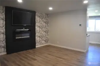 Rooming living area with electric fireplace and trendy wall covering.