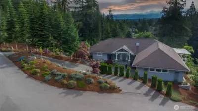 Located on 1.26 acres, this stunning home is on a cul-de-sac in a gorgeous neighborhood. West-facing views of the Olympic Mountains peak out above the clouds. Note the circular driveway for ease of parking.