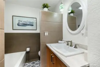 The primary bath features a vanity with quartz countertops, a soaking tub, and a separate shower.