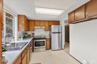 Kitchen view showing brand new refrigerator with doorway leading to hallway.