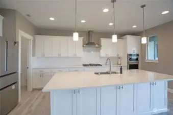 The kitchen island features hidden extra cabinets beneath the sleek Quartz countertop.