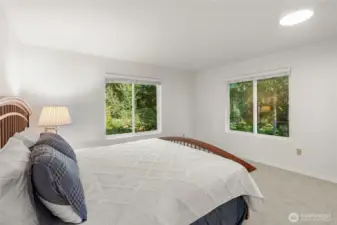 Primary bedroom is king size space with windows overlooking the lush greenery.