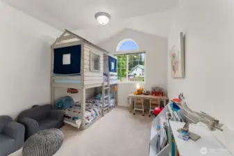 Bathed in natural light and featuring vaulted ceilings, this versatile bedroom offers ample space for sleep, study, and play. A perfect canvas for creating a personalized retreat for kids or guests alike.