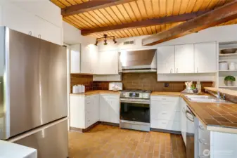 Kitchen with wood ceiling has an elevated bar area for serving or dining.