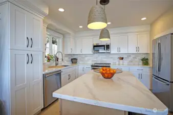 New light, bright and efficient kitchen with beautiful new cupboards, island, quartz and tile.