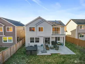 Back of home featuring expansive deck, hot tub, and balcony of the Primary Suite.