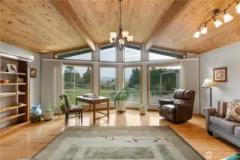 Living room featuring a stunning wall of windows, gleaming hardwood floors, and wood-lined ceilings that draw your eye toward a gorgeous mountain view.