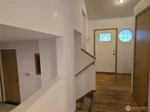 View from kitchen eating area toward front entrance of home, with galley opening to the family room on left. Stairs to upstairs also on the left.