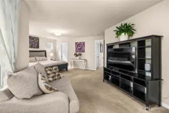 Spacious light filled primary bedroom with sitting area, en suite bath and two walk in closets.