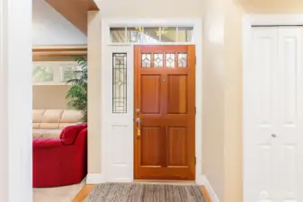 Entry door with leaded glass panel and transom window above adds architectural character and brings in natural light.  One of the many closets on the right side of this photo.