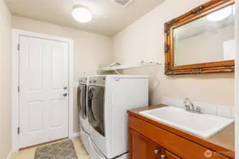 Utility room with sink. Door leading to the 3 car garage. Washer and dryer convey.